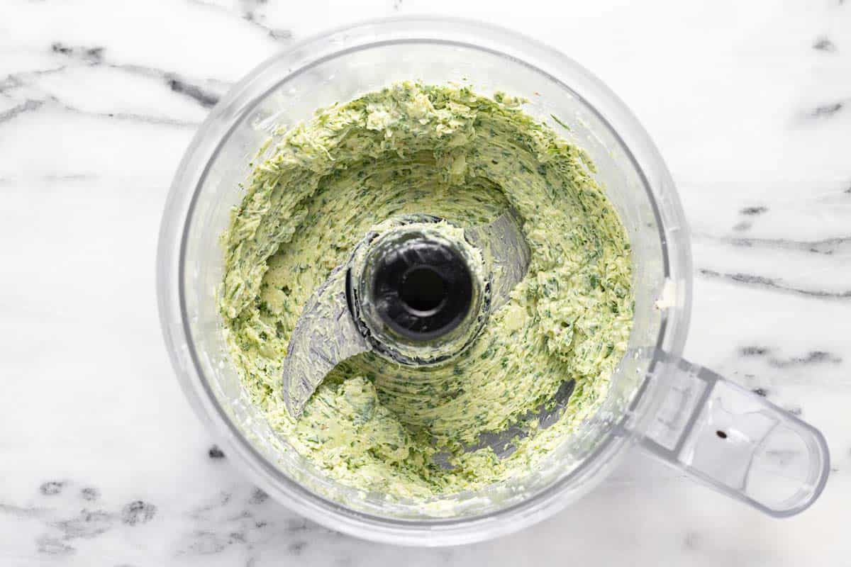 Food processor filled with homemade garlic butter. 