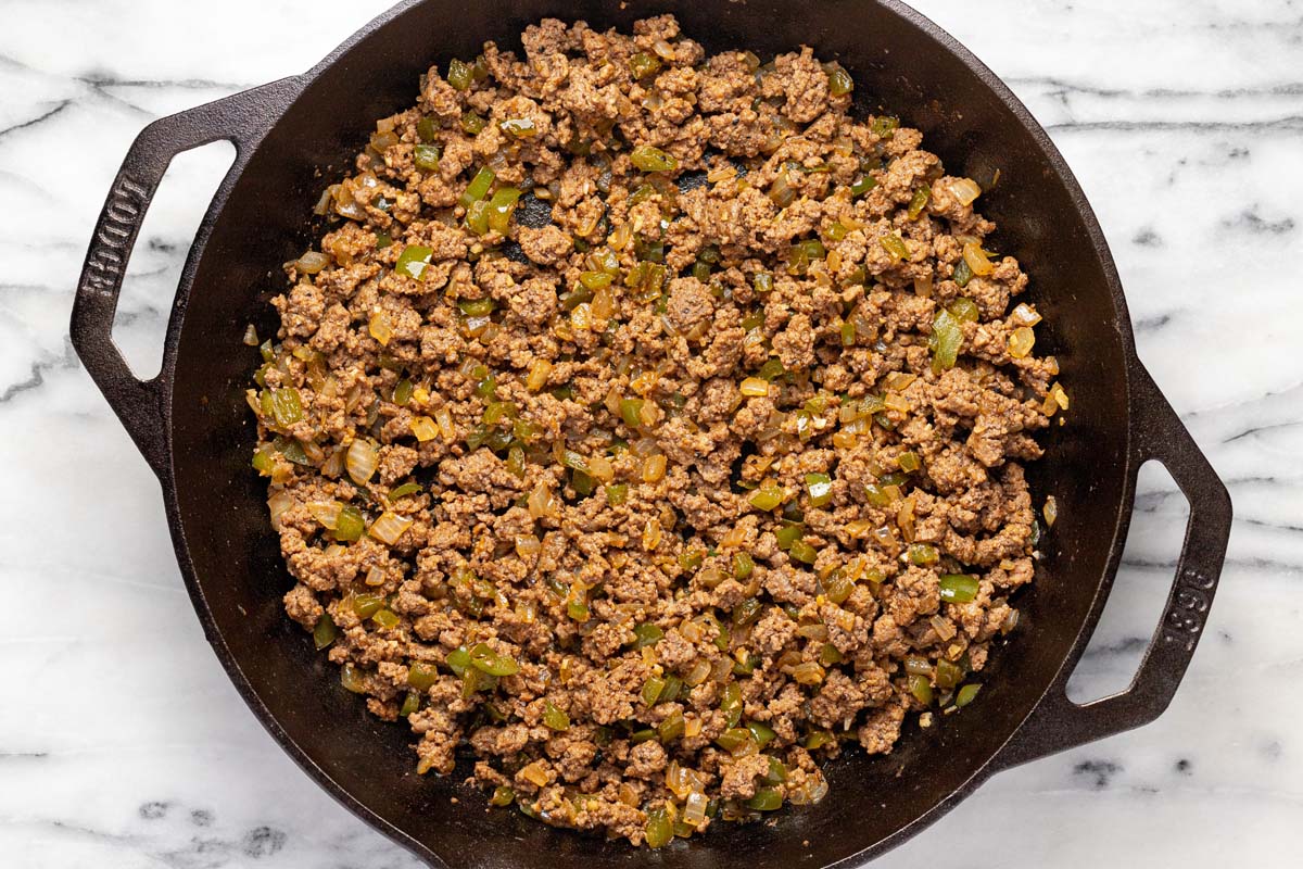 Browned ground beef and veggies in a cast iron skillet. 