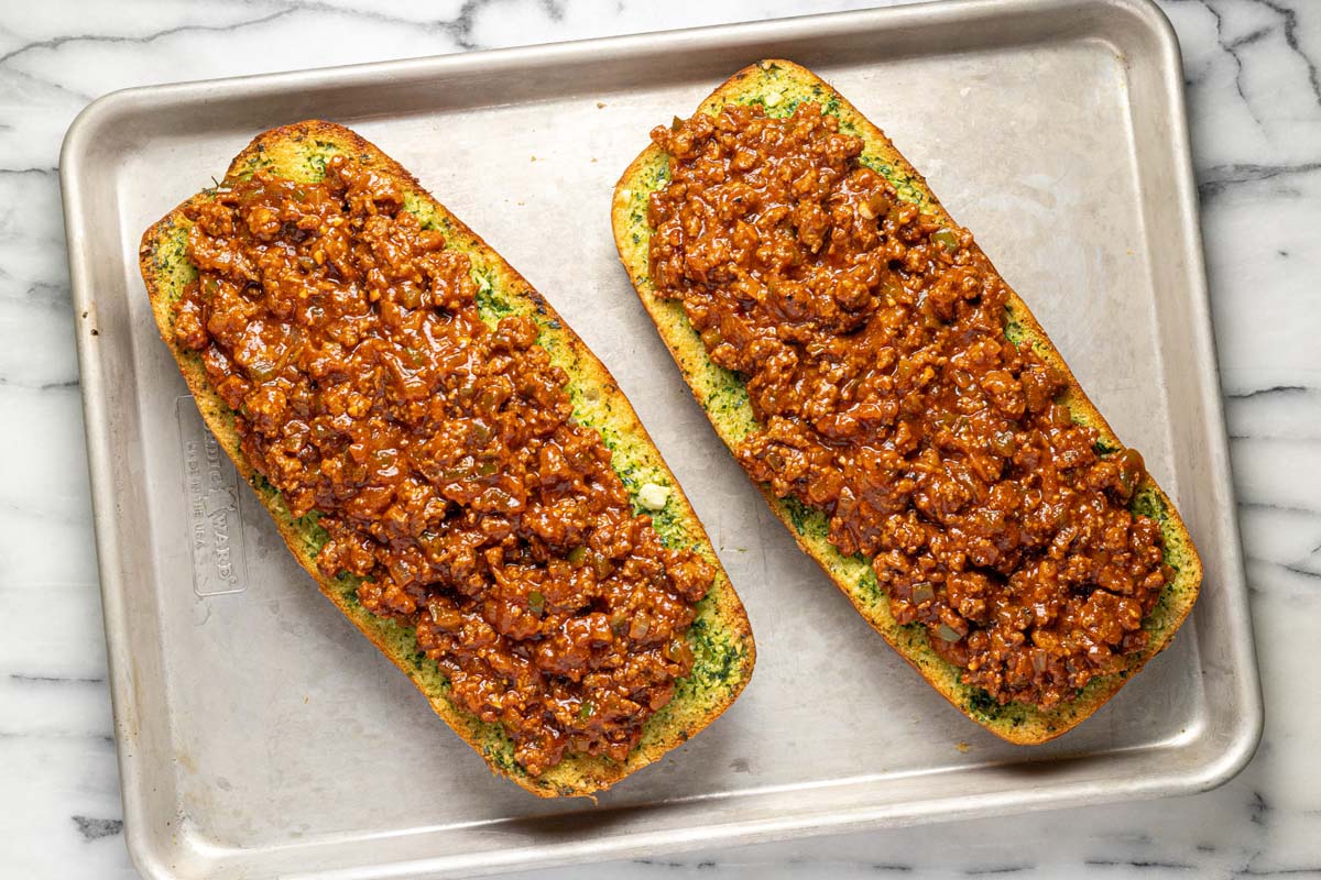 Garlic bread with sloppy joe mixture spread across it. 