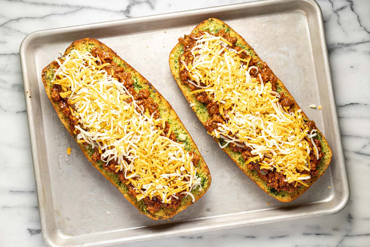 Shredded cheese on top of sloppy joe mixture on garlic bread. 