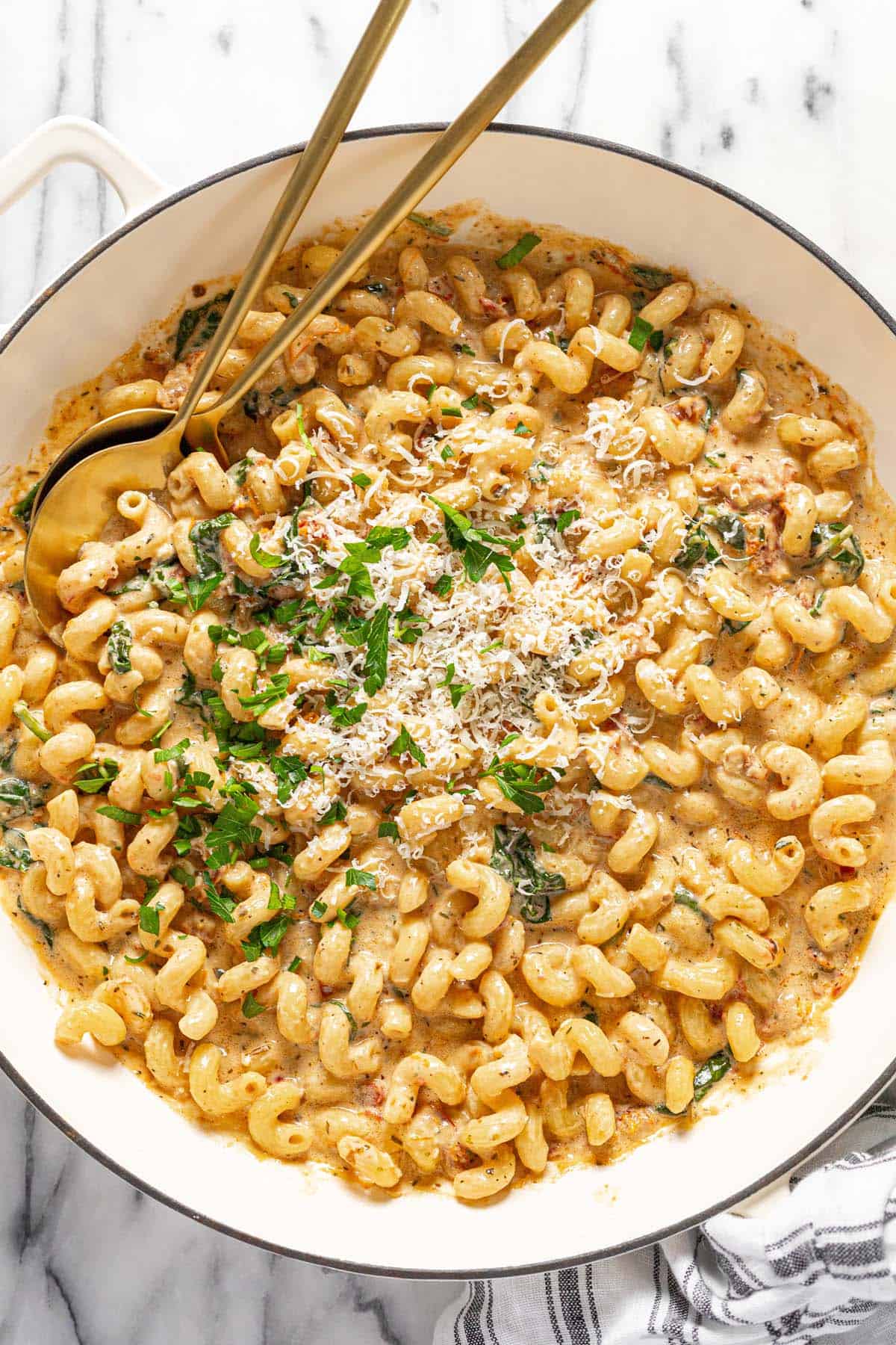 Large pan filled with creamy sun-dried tomato pasta garnished with parsley and Parmesan. 