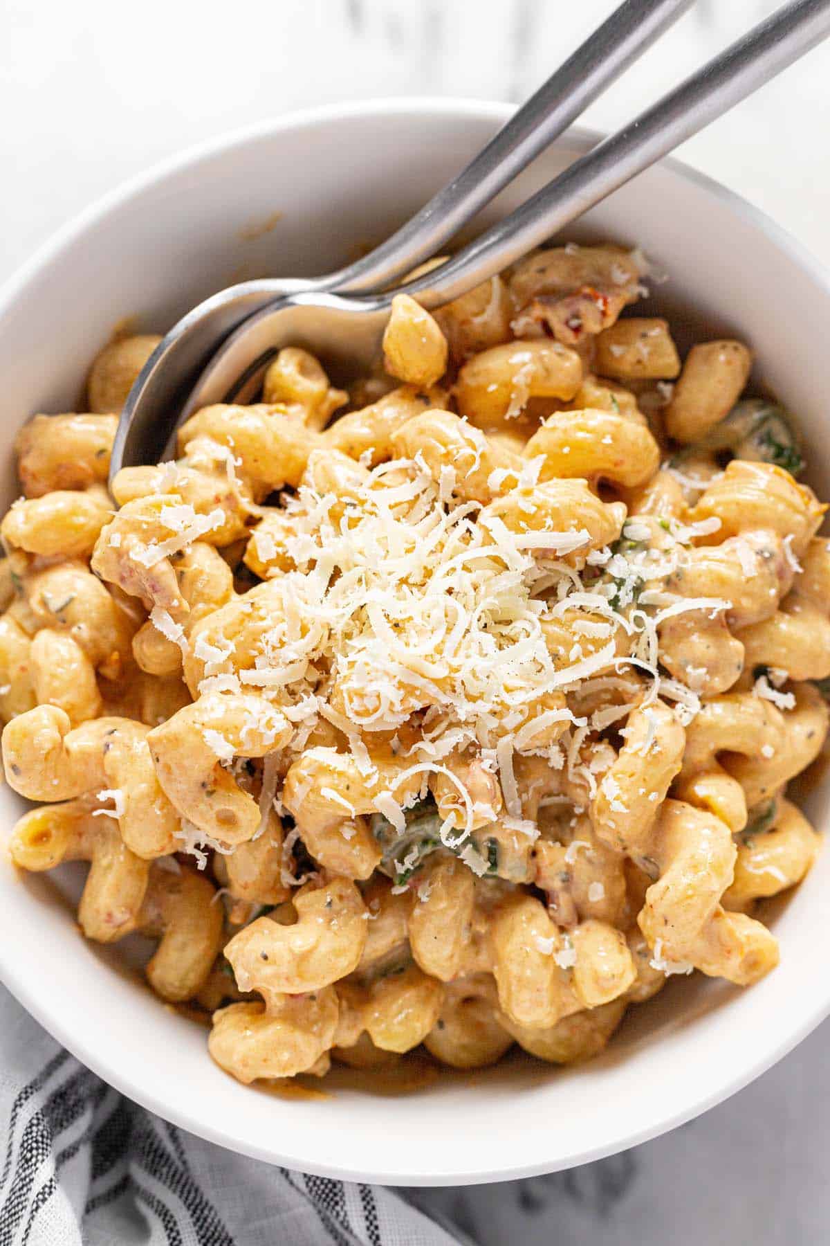 Bowl filled with creamy sun-dried tomato pasta garnished with Parmesan. 