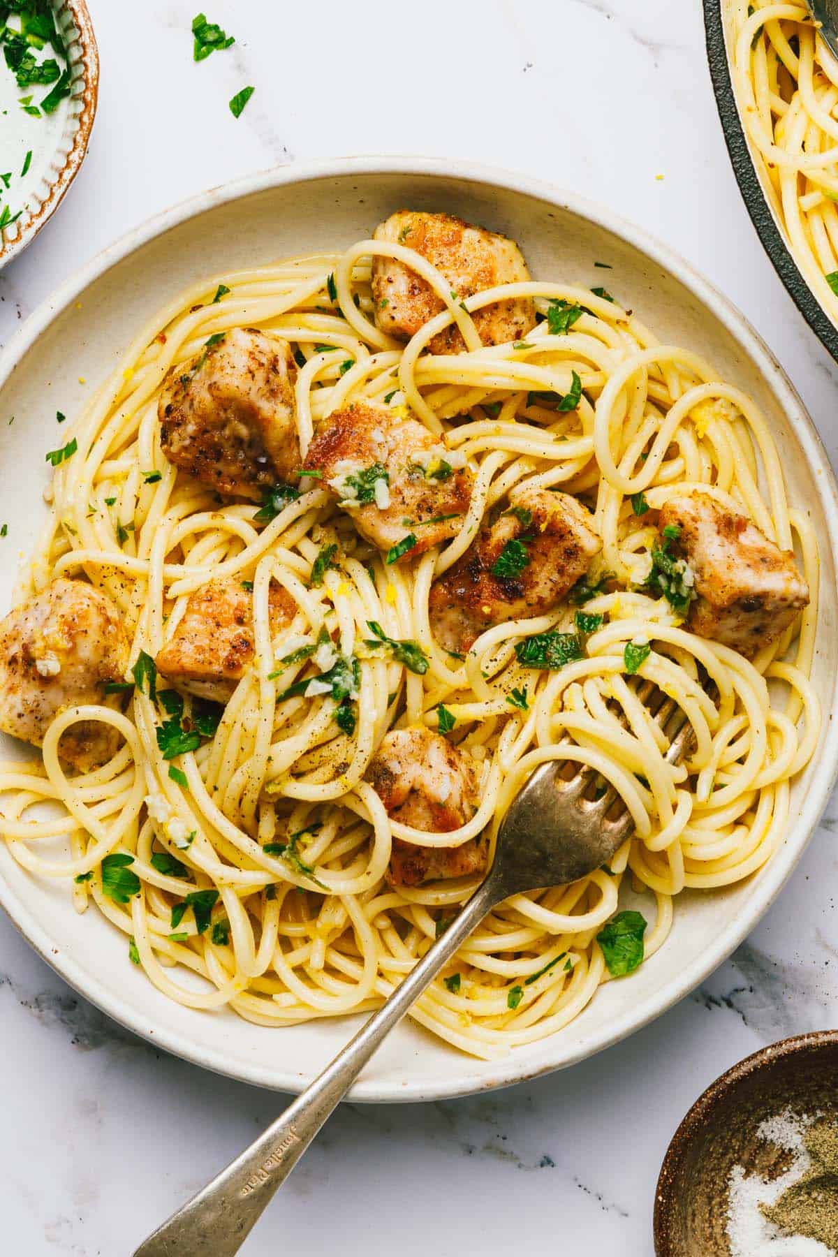 Chicken scampi garnished with fresh parsley in a bowl with a fork. 