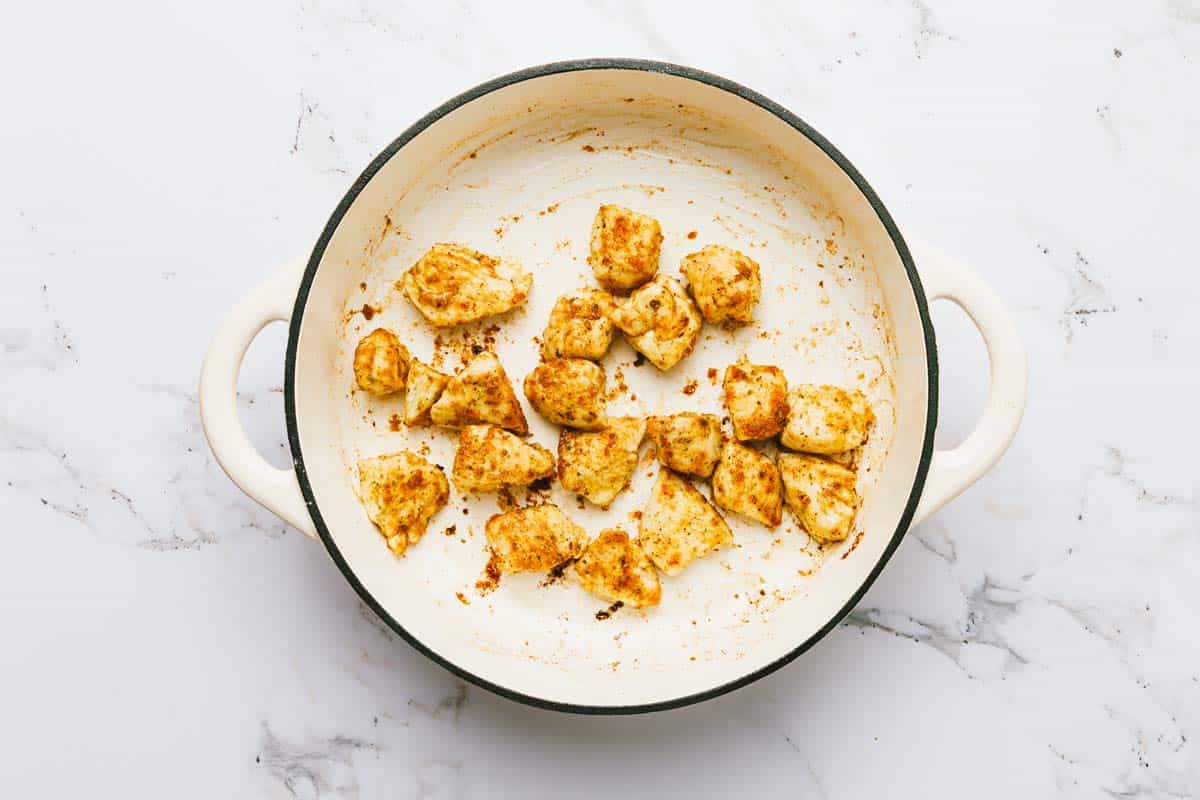 Pieces of sauteed chicken in a large pan. 