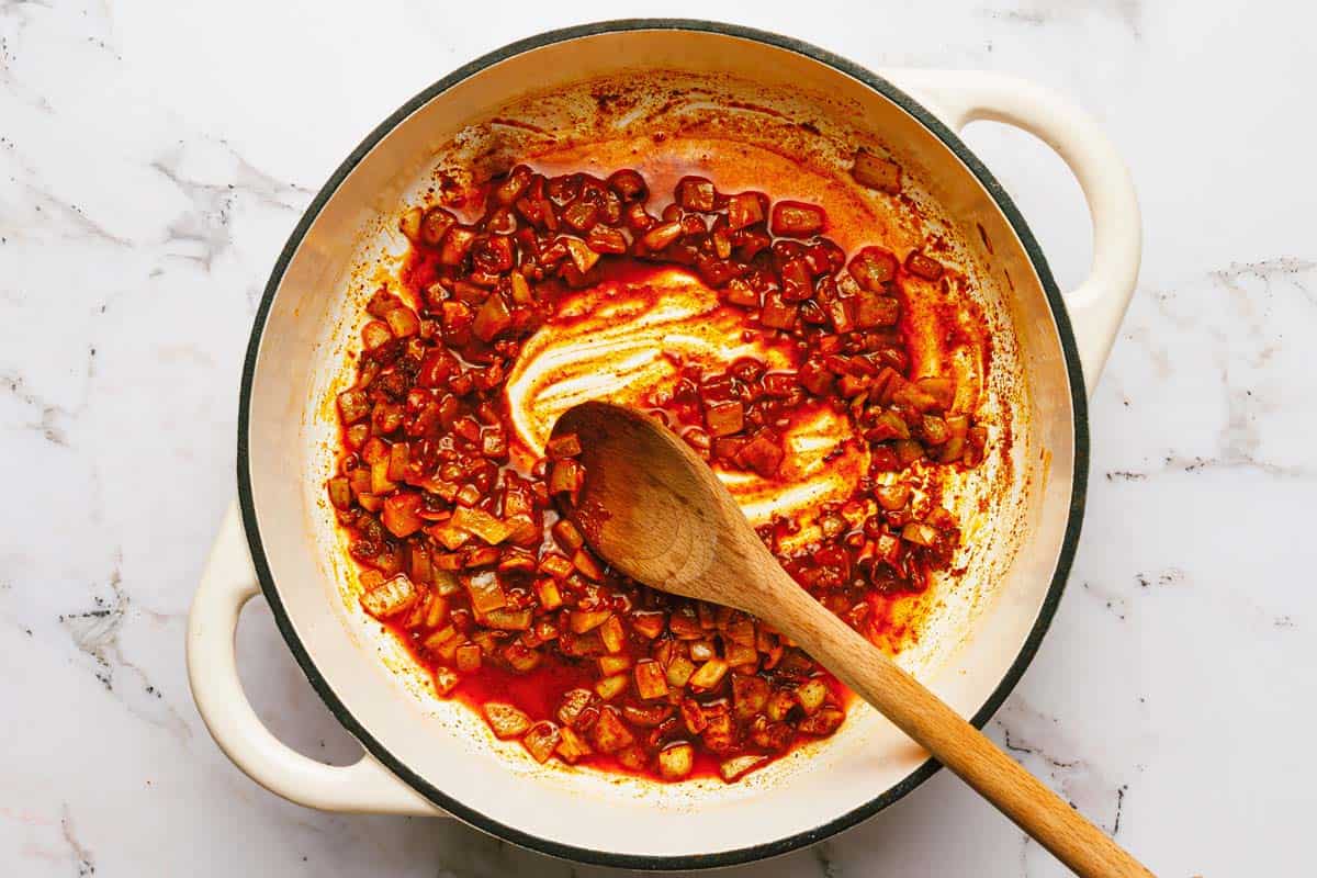 Large pot filled with sauteed onions and garlic with taco seasoning. 