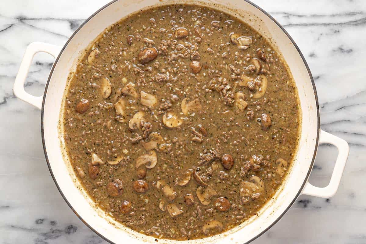 Large pan filled with ingredients to make beef stroganoff sauce. 