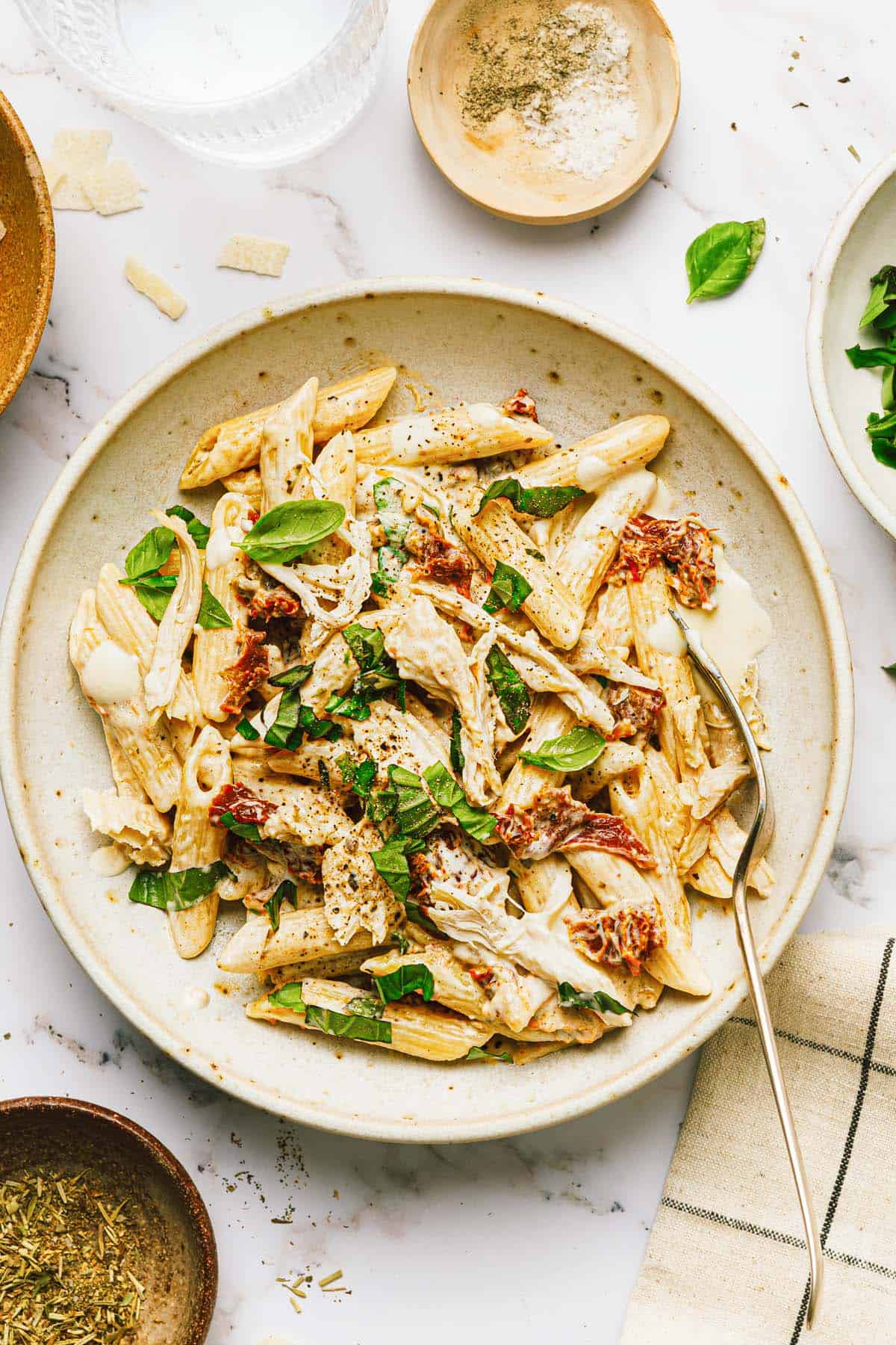 Bowl of marry me chicken penne pasta garnished with fresh basil. 