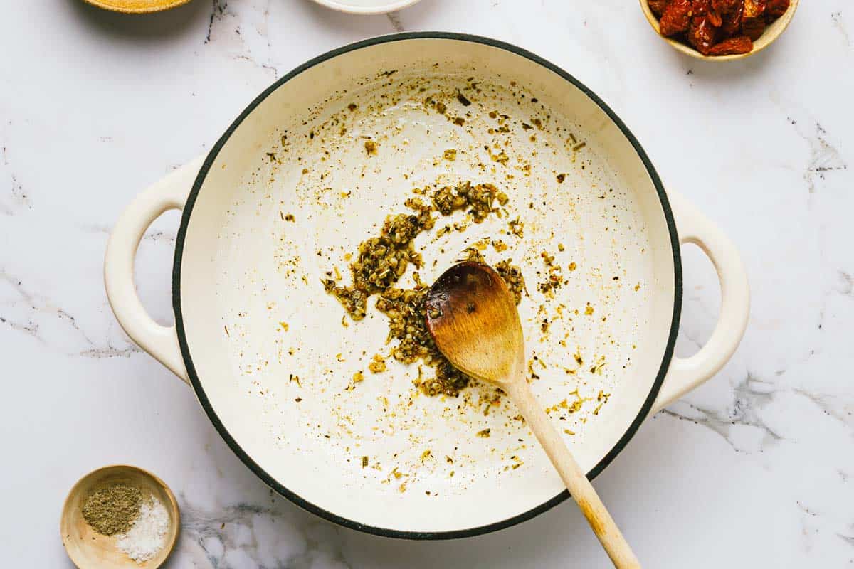 Large pot filled with sauteed garlic and dried herbs. 