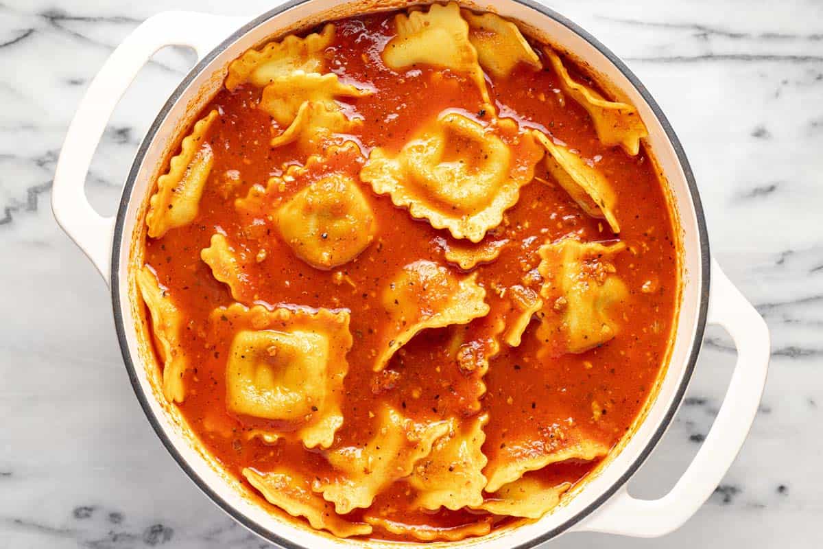 Ravioli cooking in a tomato broth. 