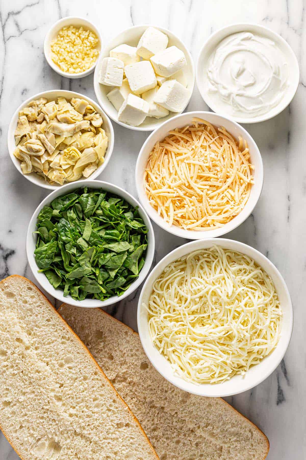 Bowls of ingredients to make spinach and artichoke bread. 