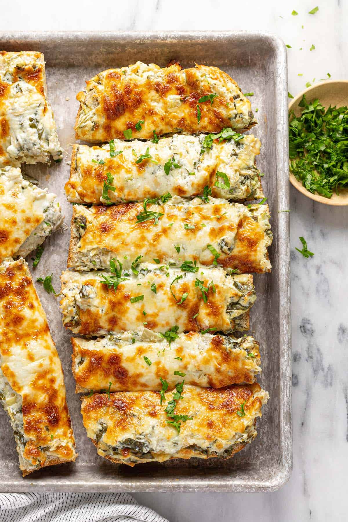 Sliced spinach and artichoke bread on a small baking sheet. 