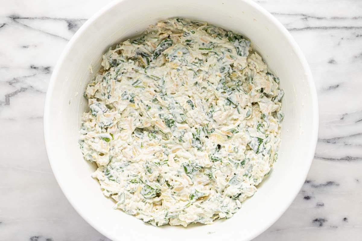 Ingredients for spinach and artichoke dip mixed together in a large bowl. 