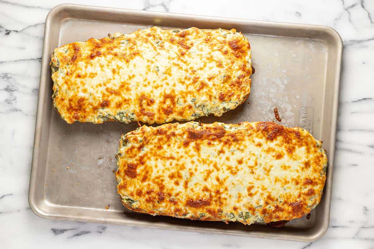 Freshly baked spinach and artichoke bread on a baking sheet. 