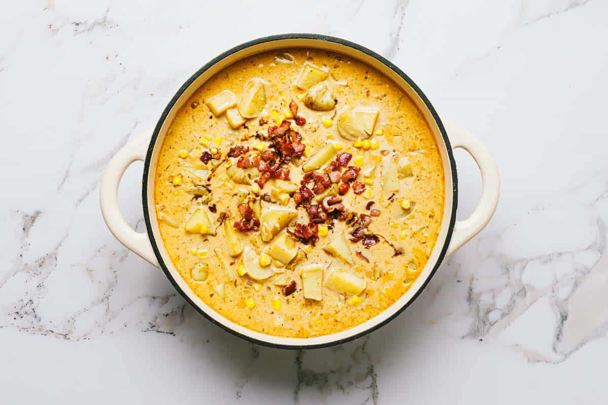 Large pot filled with creamy corn and potato chowder with bacon. 