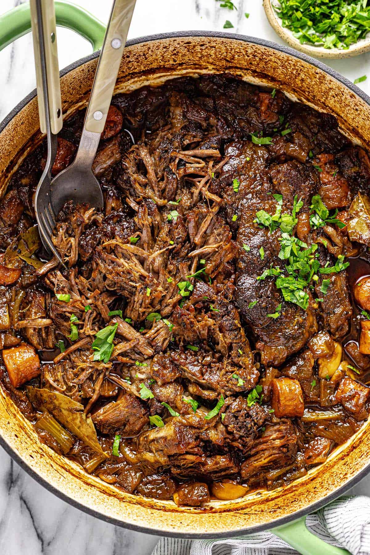 Shredded braised beef chuck roast in a large pot. 