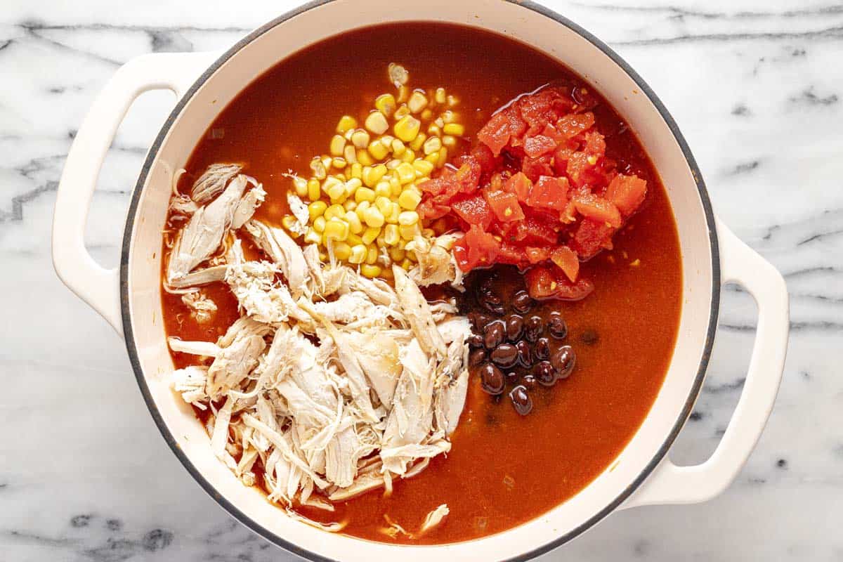 Large pot filled with ingredients to make creamy chicken tortilla soup. 