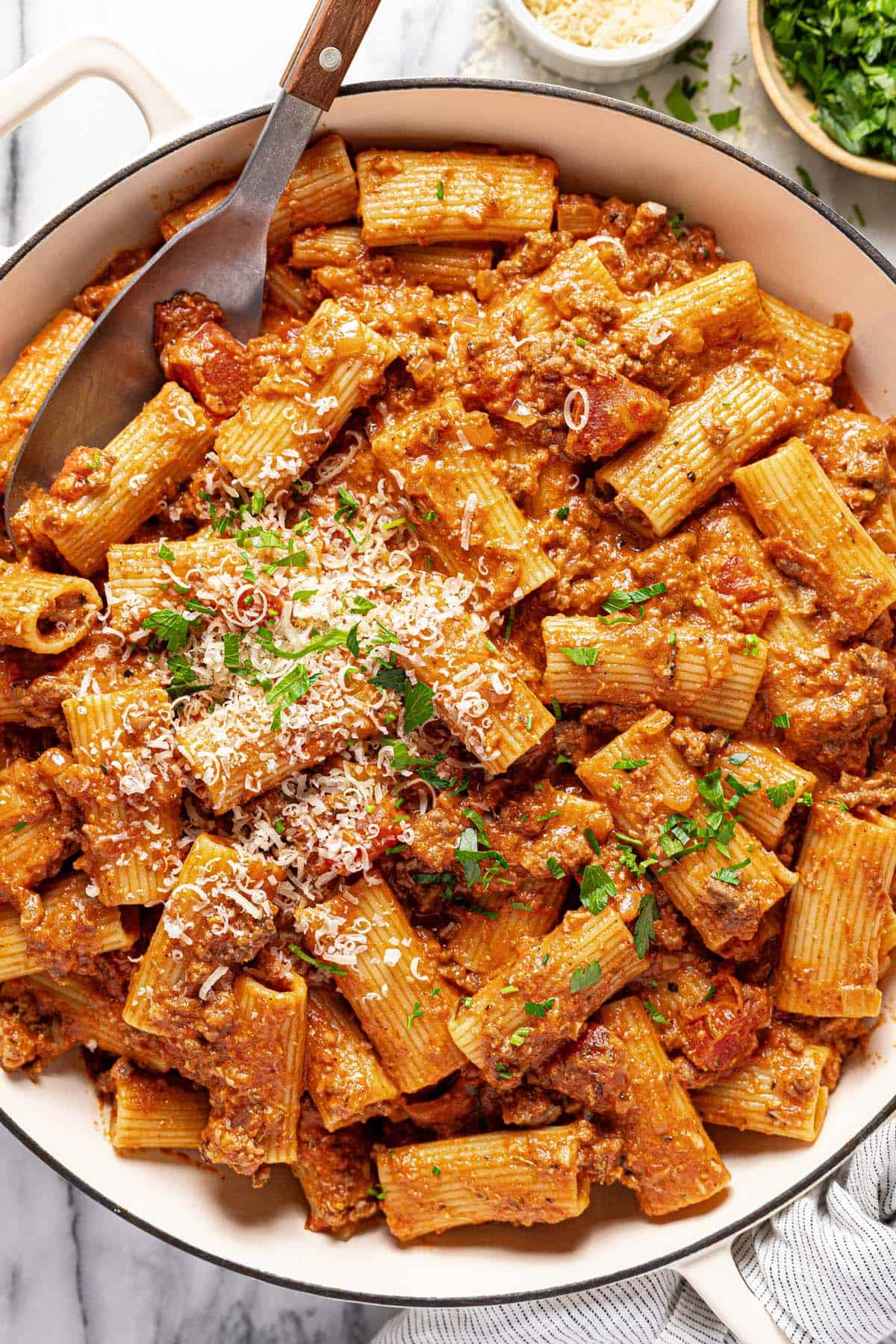 Large pan of ground beef pasta garnished with Parmesan and parsley. 