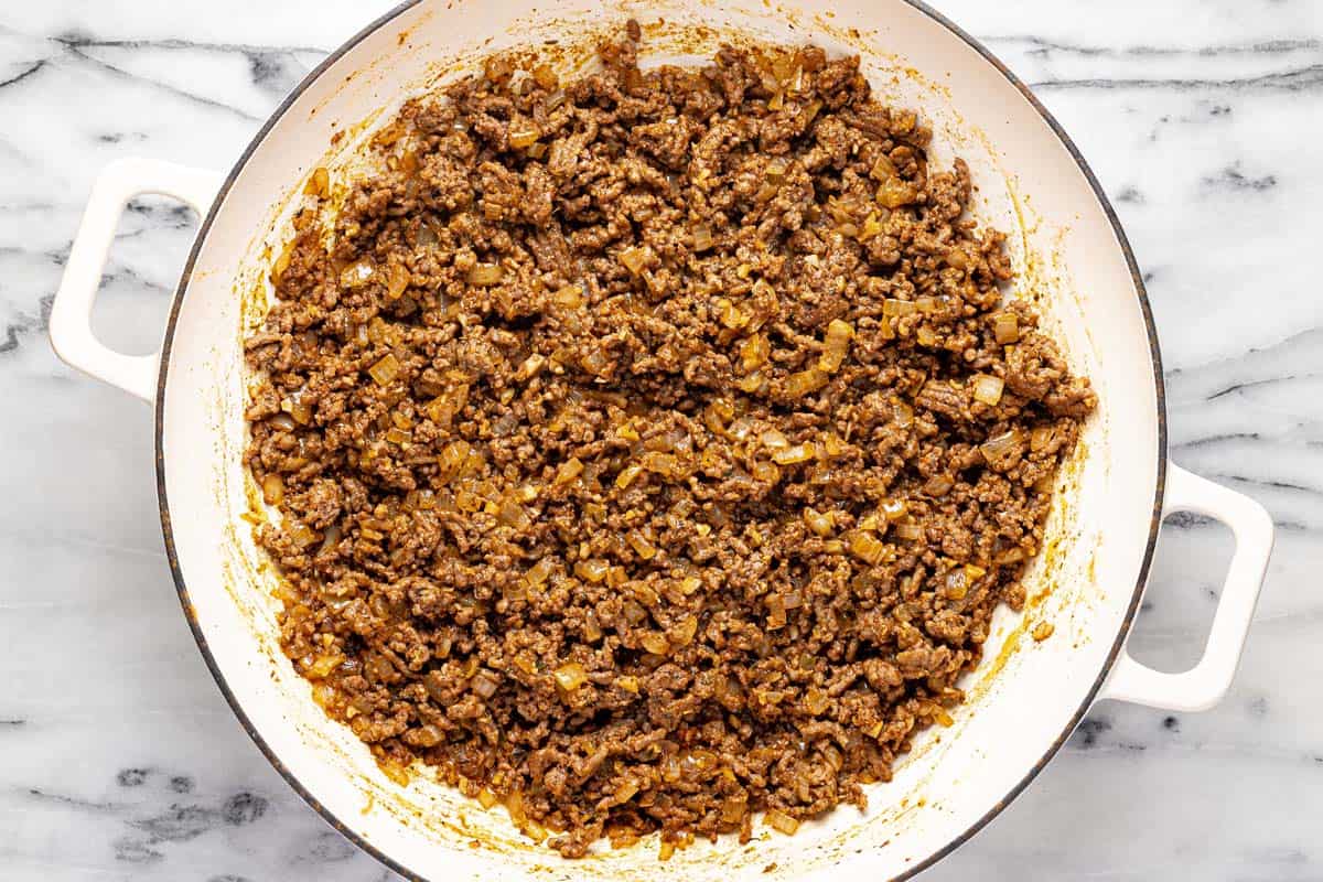 Large pan filled with ground beef and sauteed onion. 