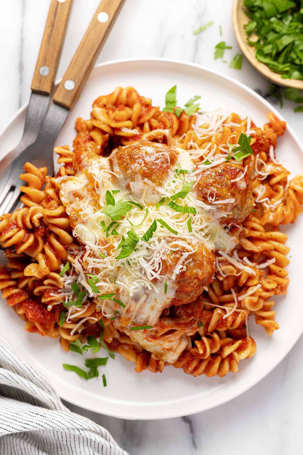 Plate filled with pasta, meatballs, and cheese. 