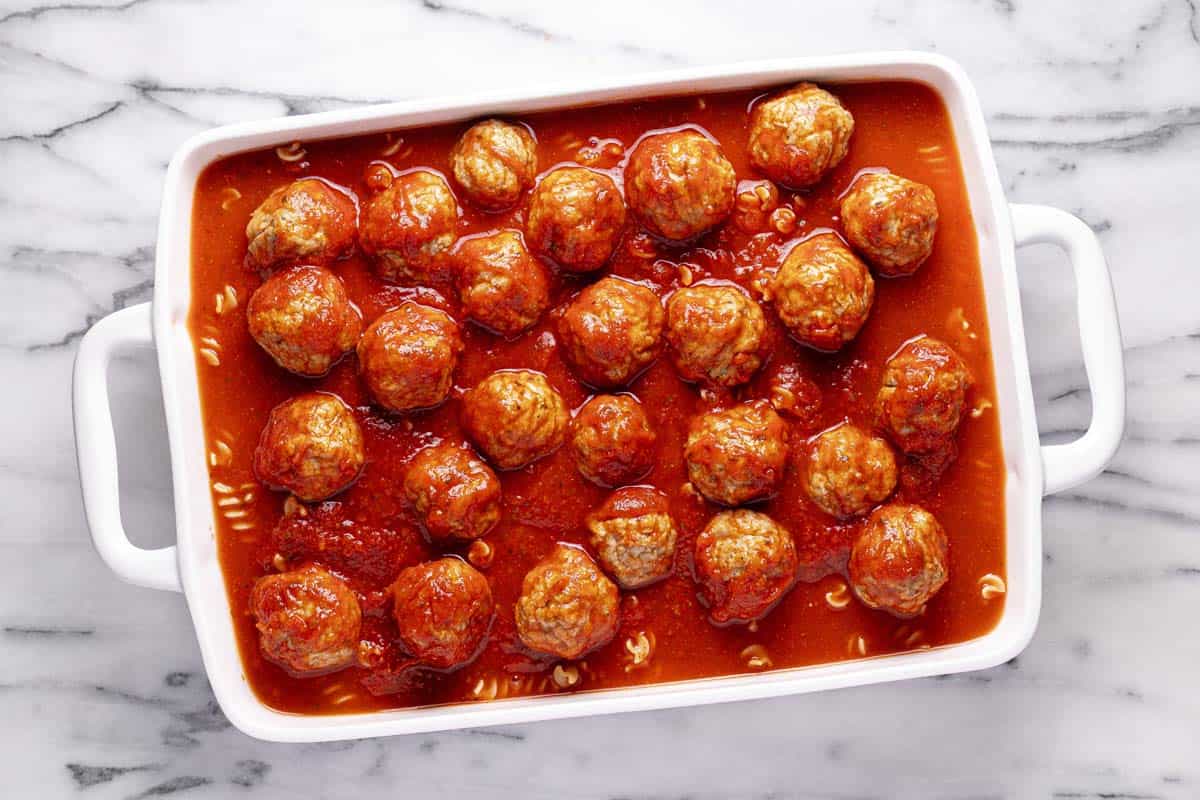 Meatballs, pasta, and spaghetti sauce in a large pan. 