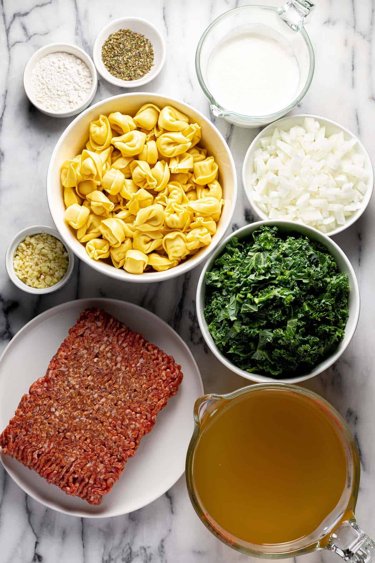 Bowls of ingredients to make sausage tortellini soup. 