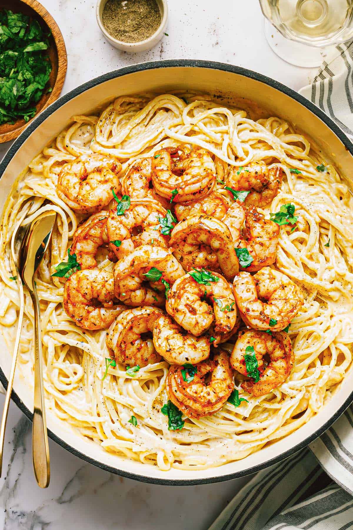 Large pan filled with shrimp alfredo garnished with parsley. 