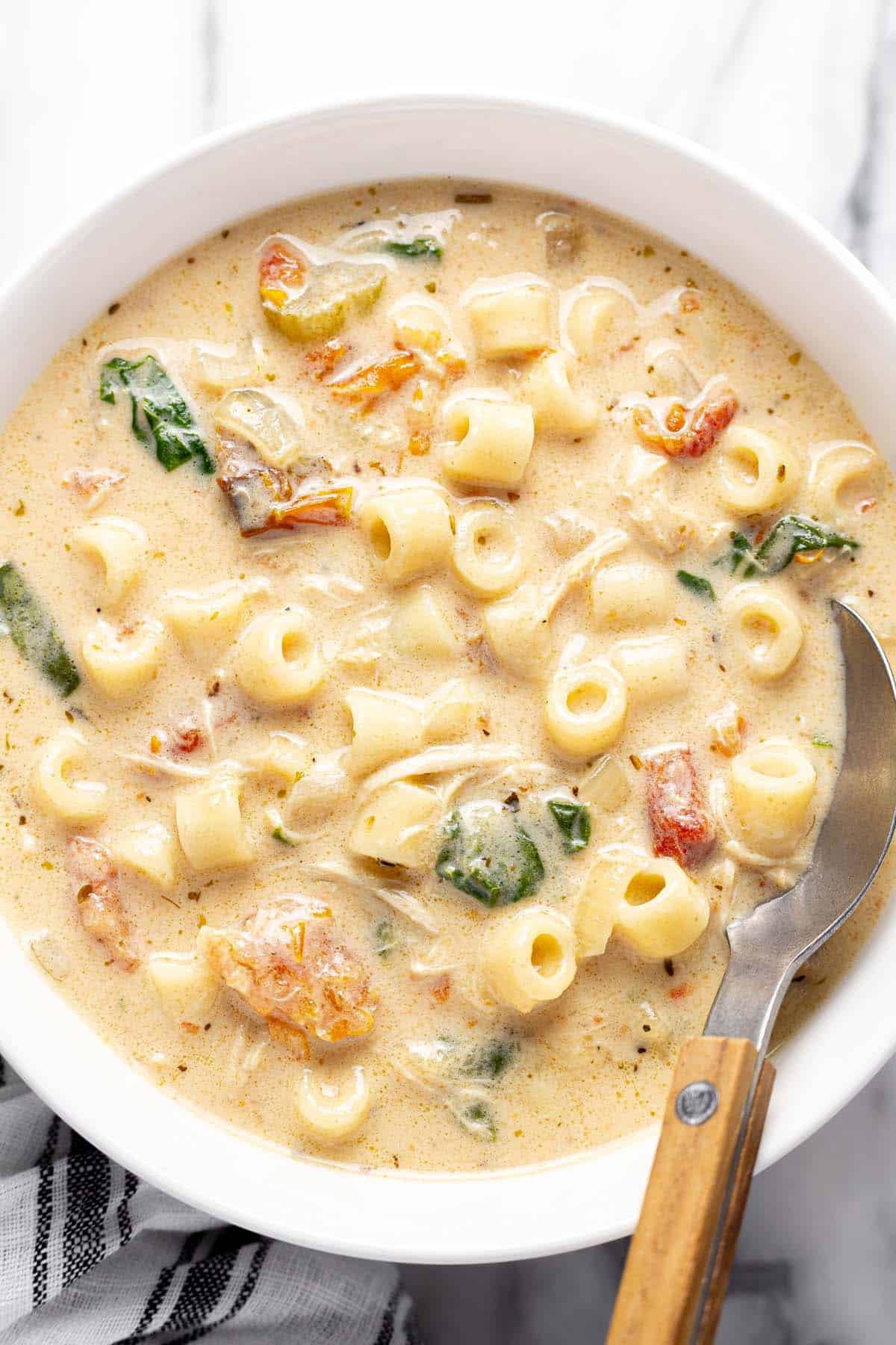 Bowl of creamy chicken noodle soup with a spoon. 