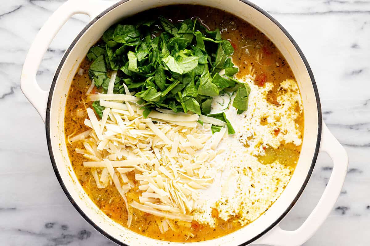 Large pot filled with ingredients to make creamy Tuscan chicken noodle soup. 