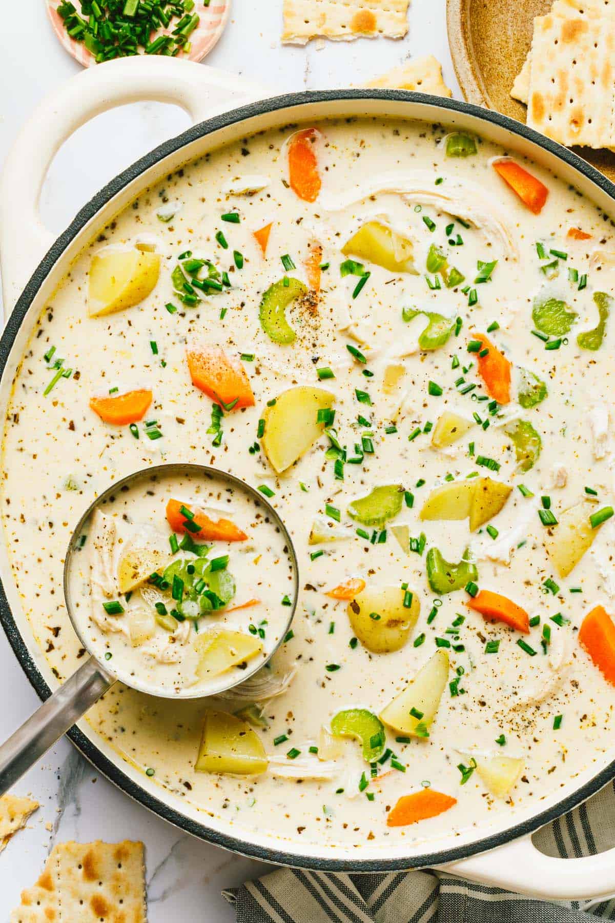 Homemade creamy chicken potato soup in a large pot garnished with chives. 