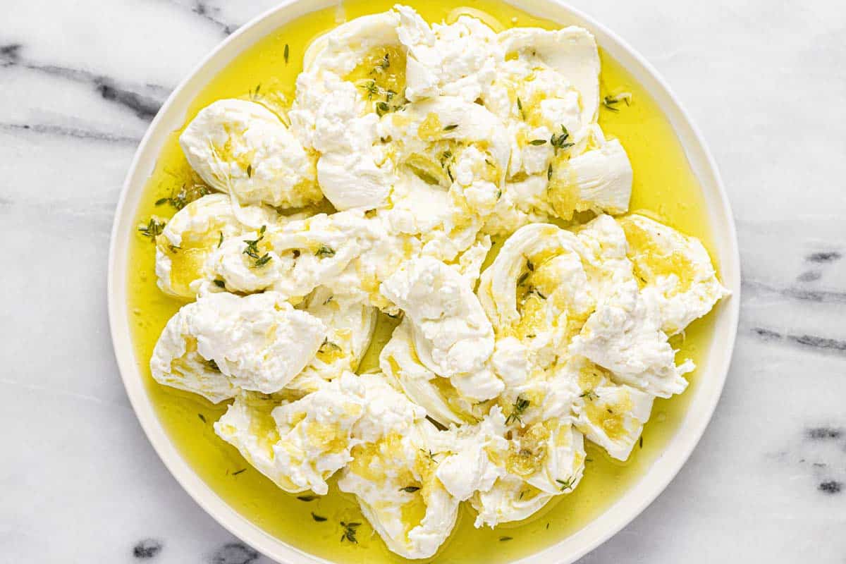 Burrata cheese on a serving plater with olive oil poured over it. 