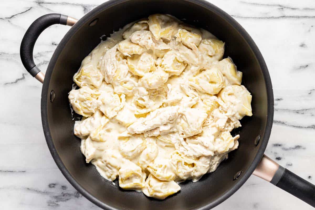 Creamy chicken tortellini alfredo in a pan. 