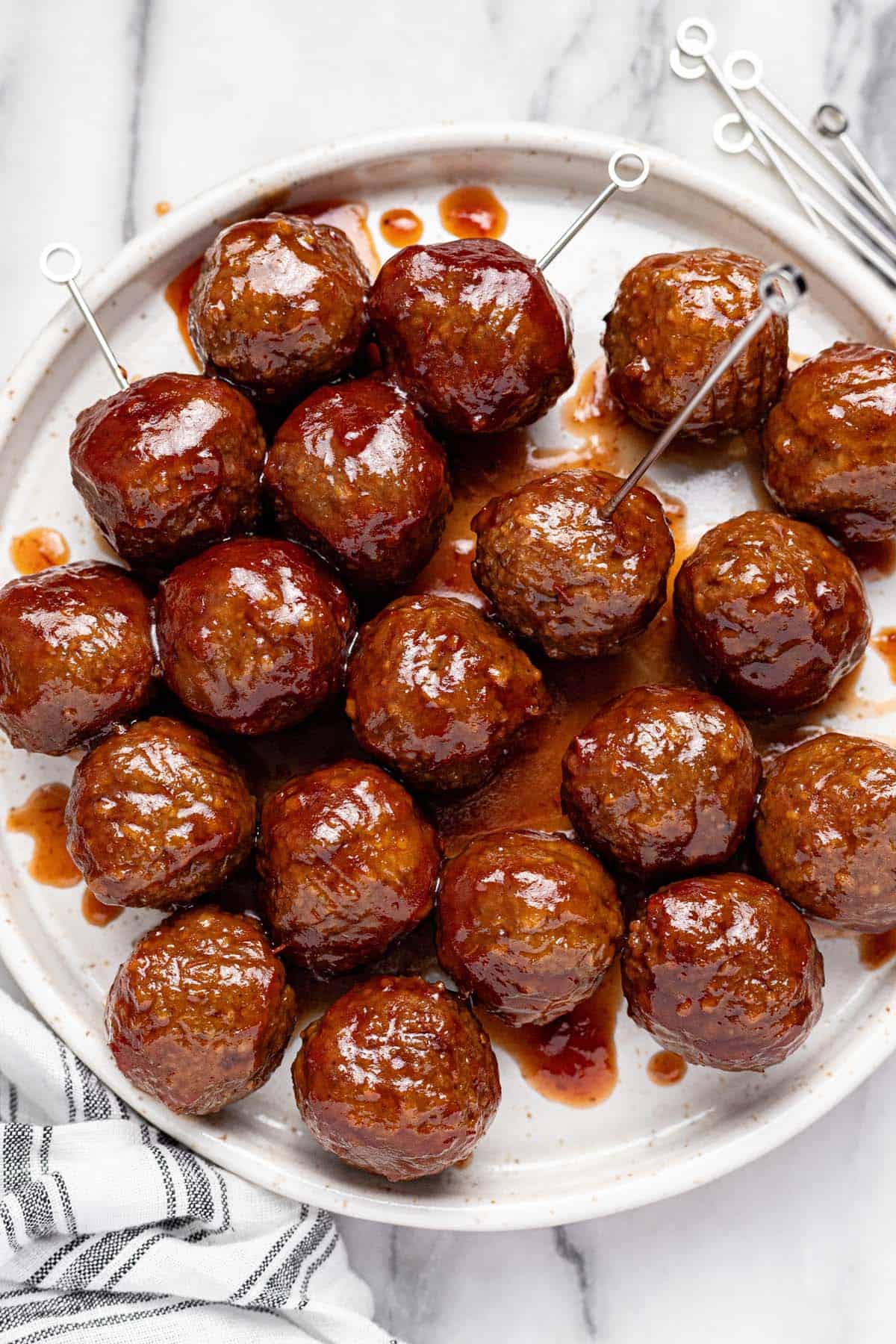 Grape jelly and chili sauce meatballs on a plate with toothipcks. 