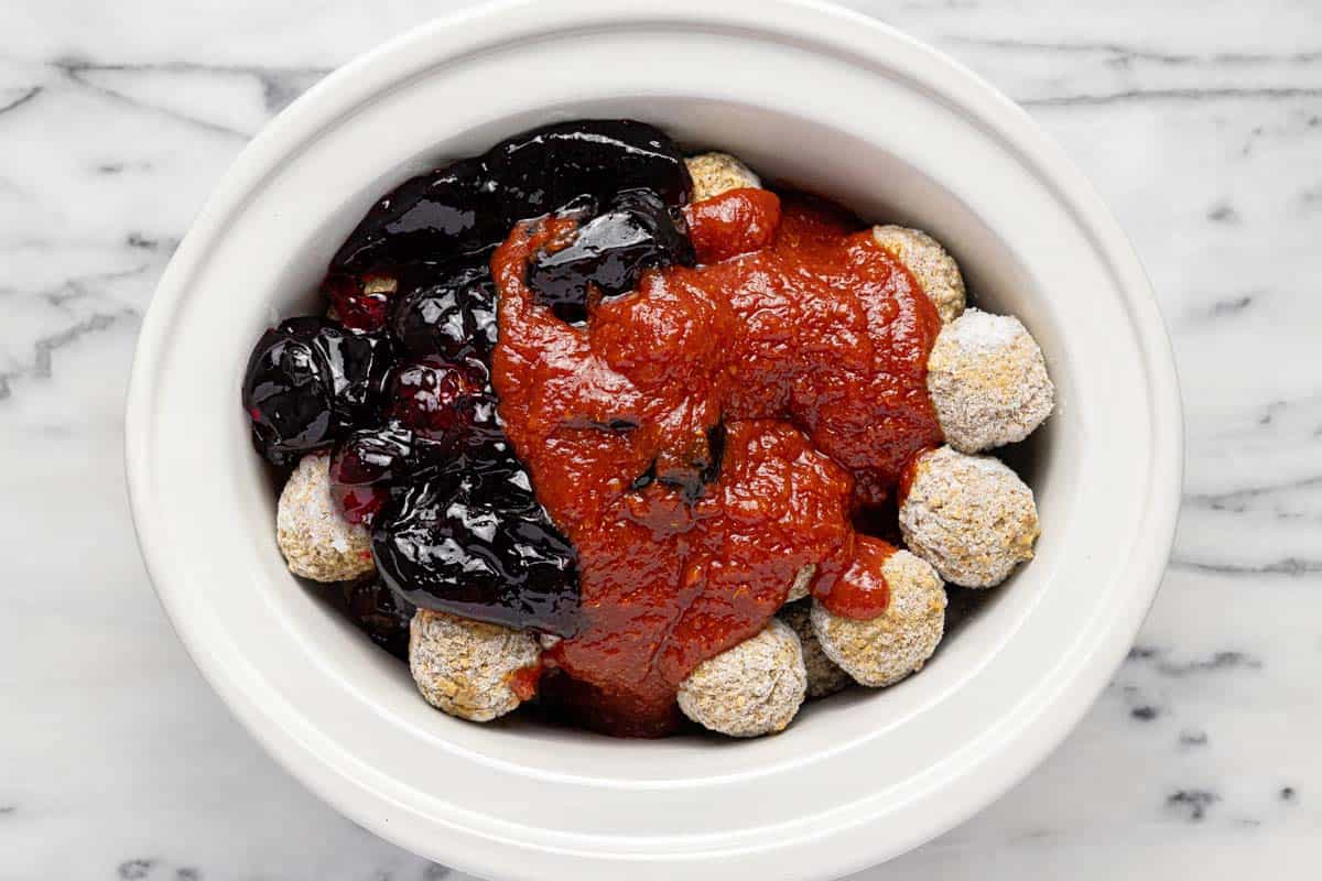 Slow cooker insert with ingredients to make cocktail meatballs. 