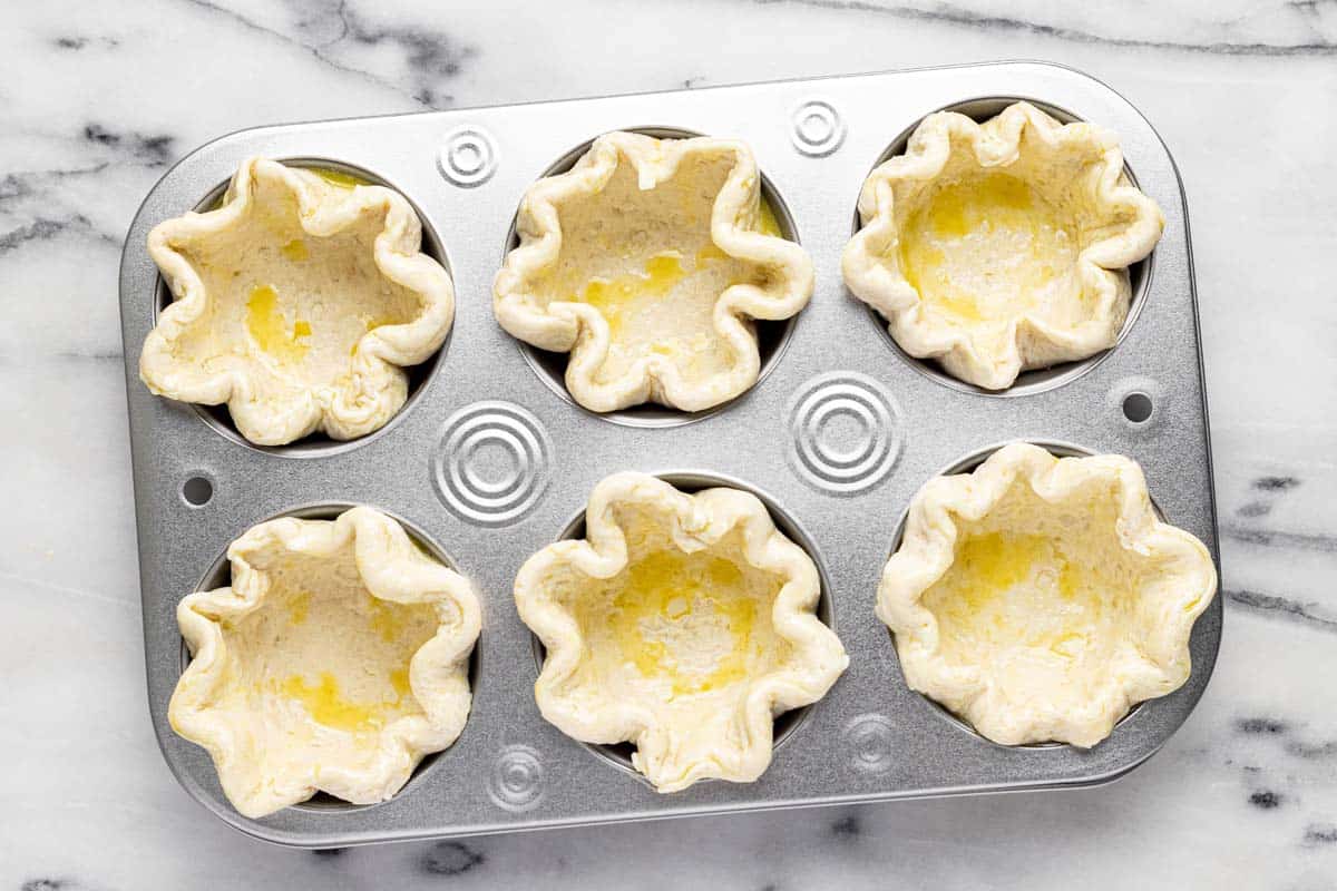 Muffin tin filled with pot pie crusts. 