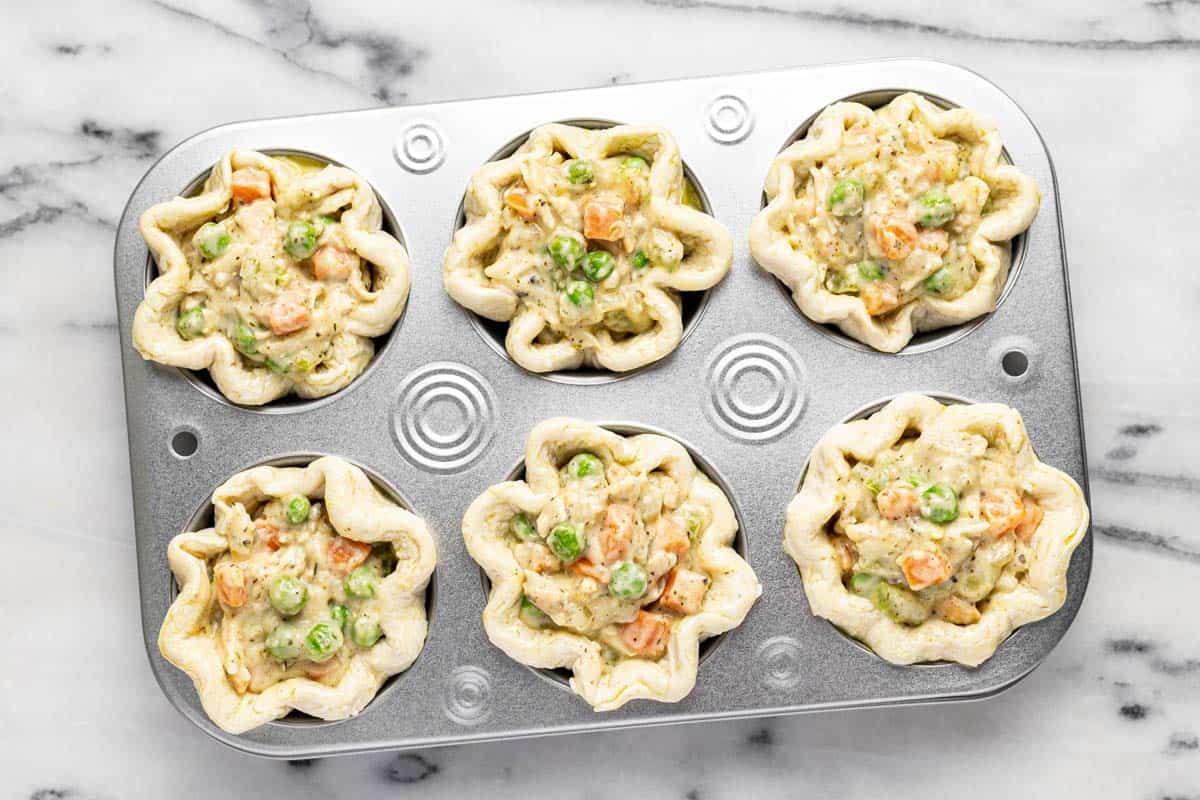 Muffin tin filled with unbaked mini chicken pot pies. 