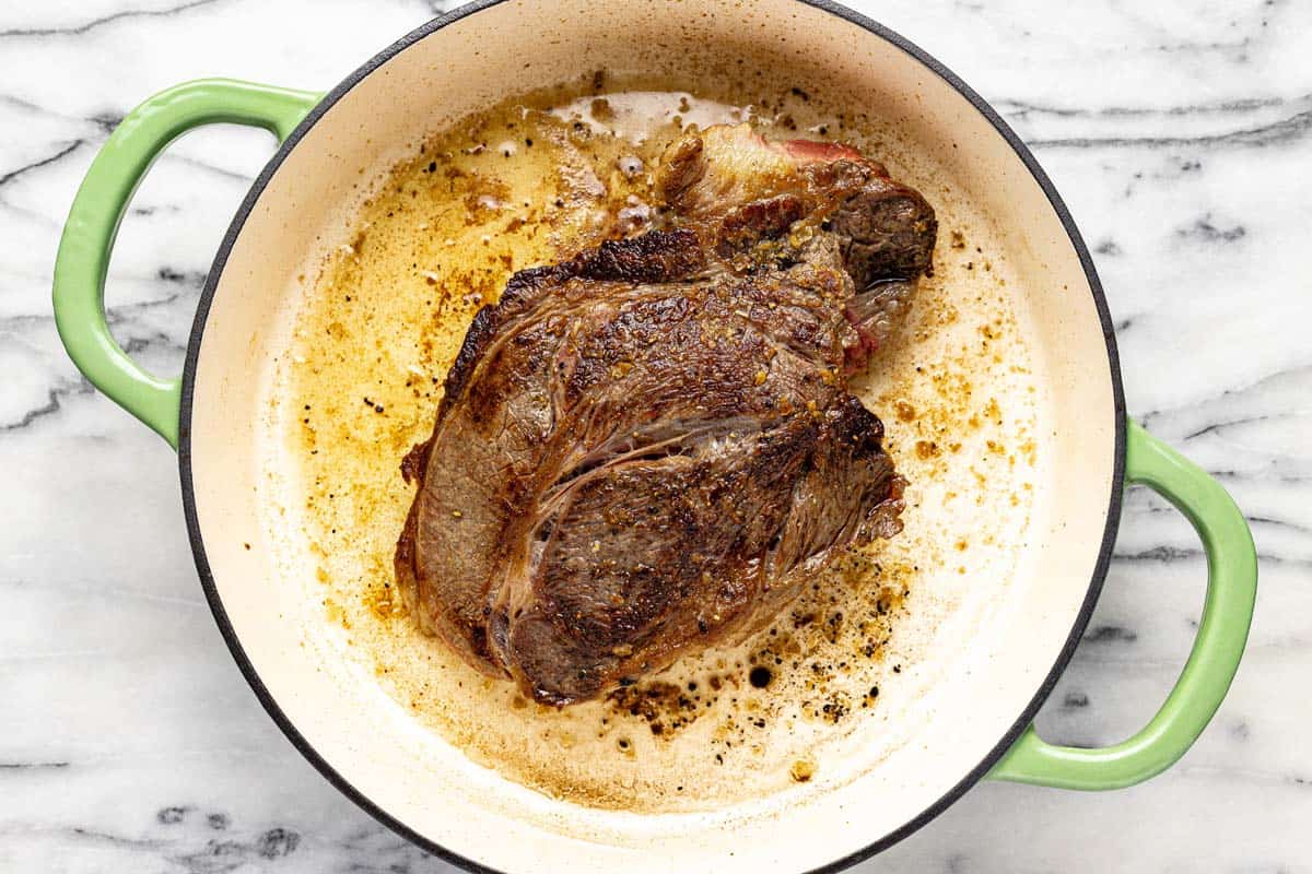 Seared pot roast in a large pan. 