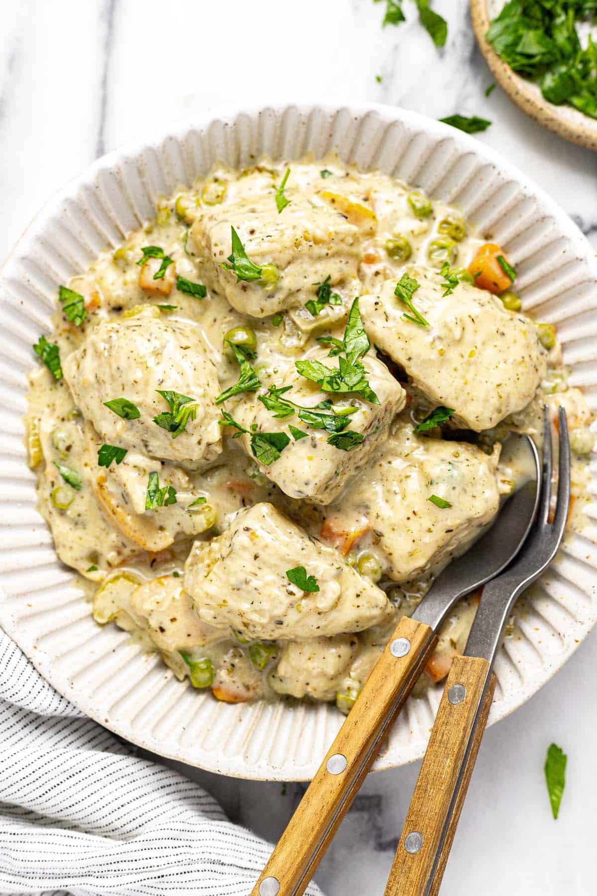 Bowl of crock pot chicken and dumplings garnished with fresh parsley. 