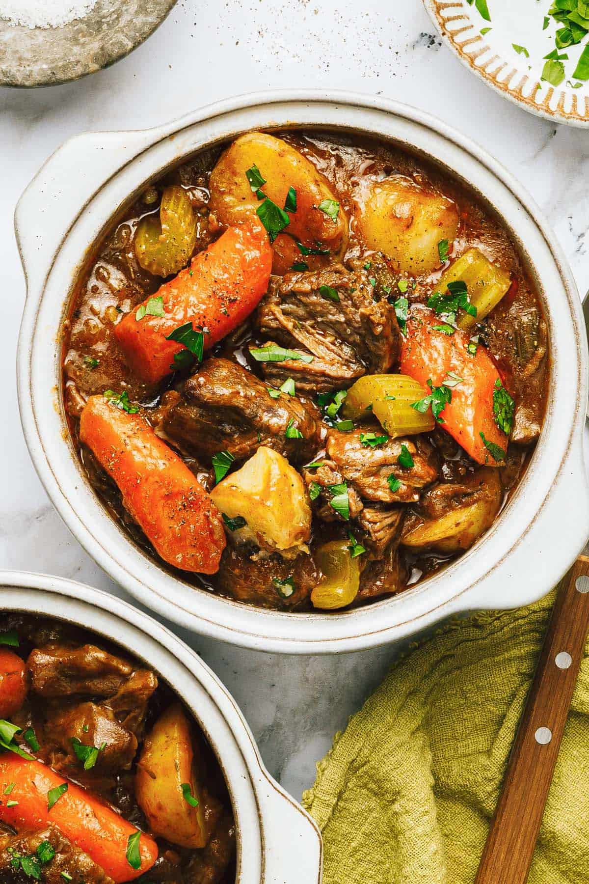 Bowl of Dutch oven beef stew garnished with chopped parsley. 