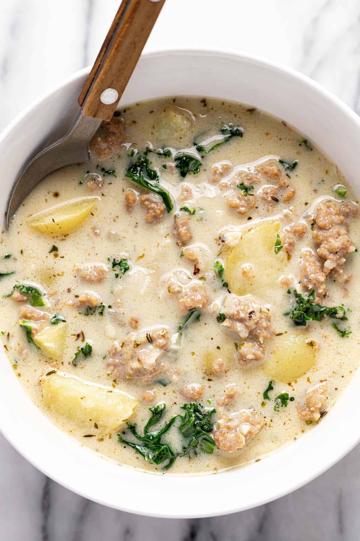 Bowl of creamy sausage, potato, and kale soup. 