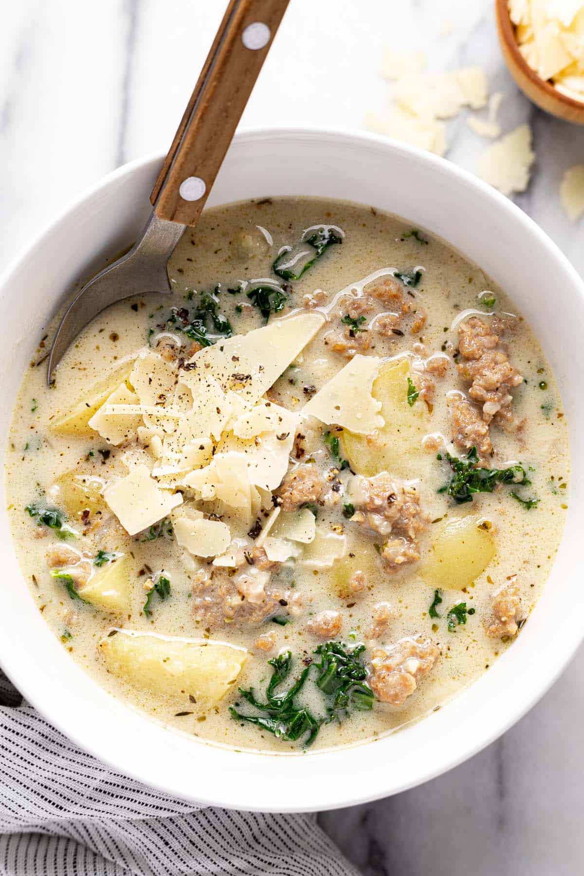 Bowl of sausage and potato soup garnished with parmesan cheese. 