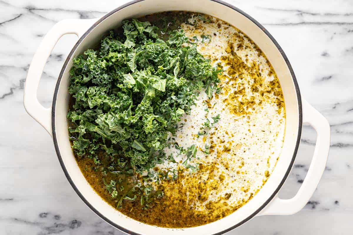 Kale and heavy cream in a large pot of sausage and potato soup. 