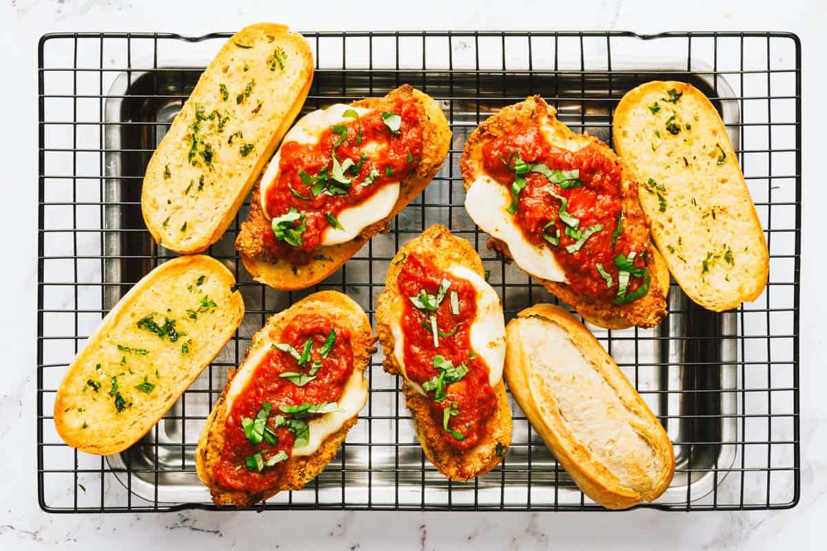 Chicken Parmesan sandwiches being assembled with marinara sauce. 