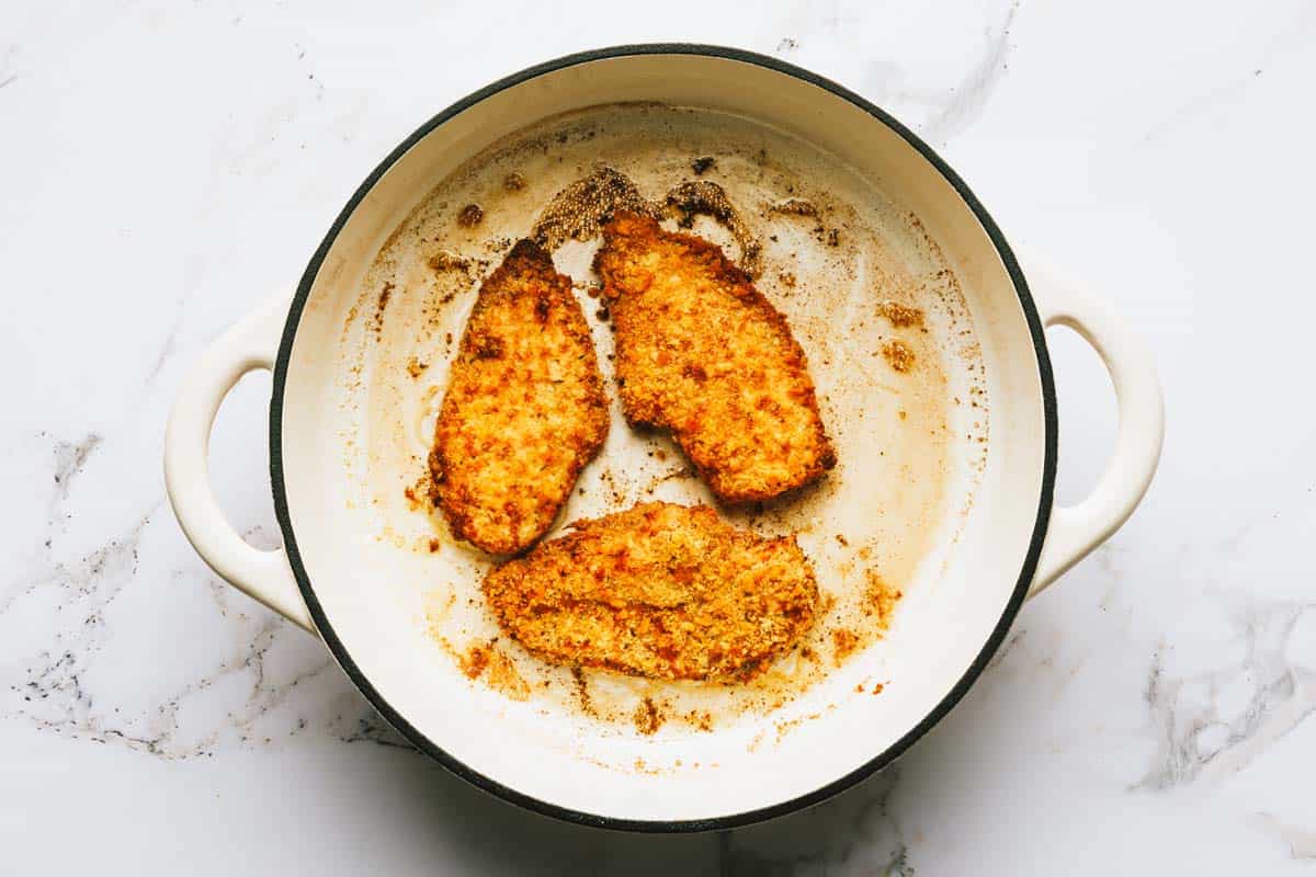 Crispy breaded chicken breast sauteed in a large pan. 