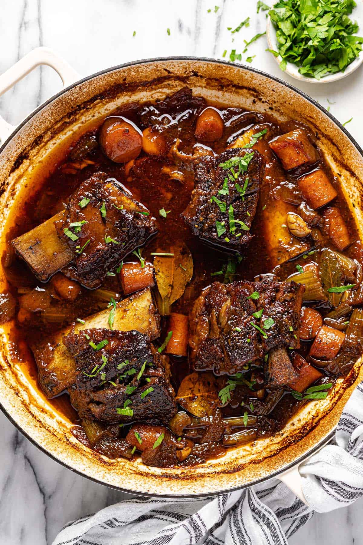 Oven braised beef short ribs in a large pan with veggies. 