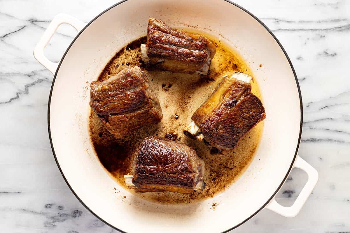 Seared short ribs in a large pan. 