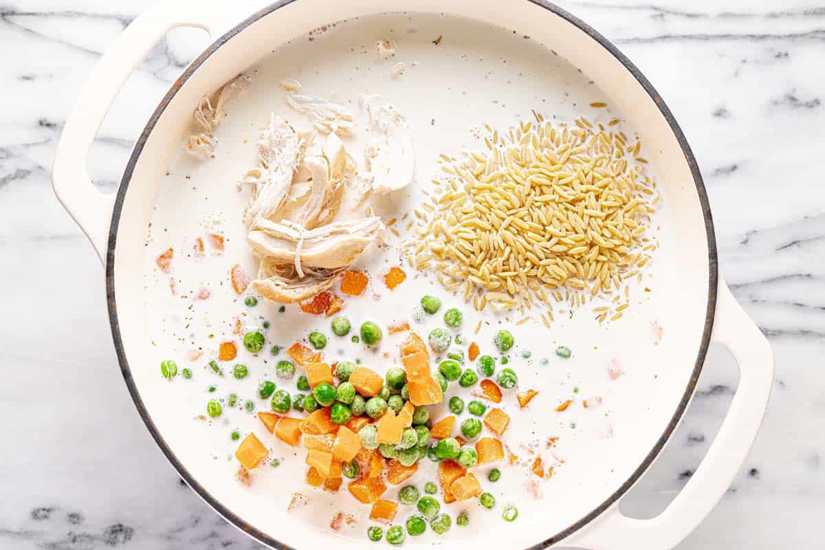 Large pot filled with ingredients to make one pot chicken and orzo. 