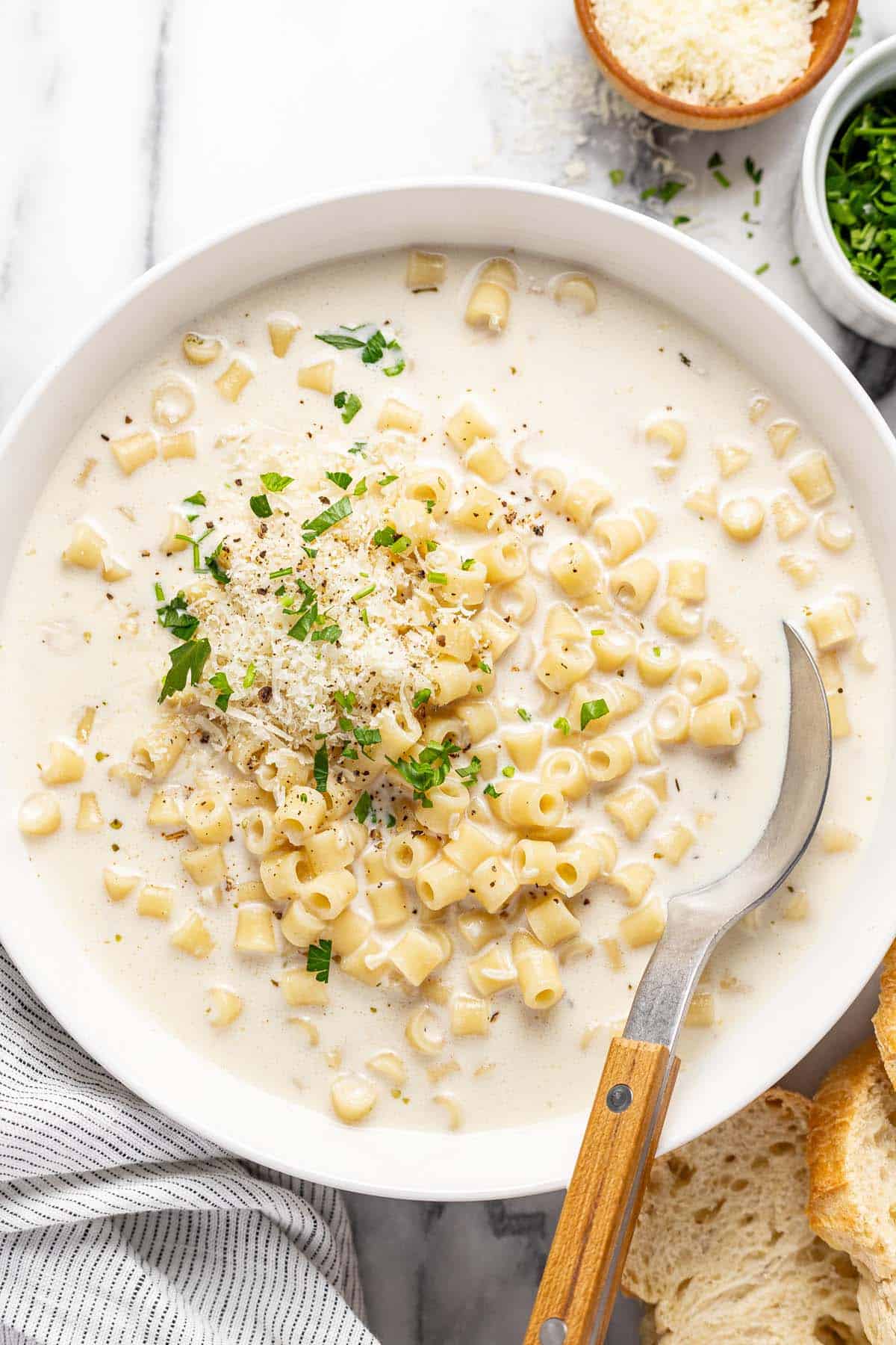 Bowl of creamy garlic Parmesan pasta soup garnised with chopped parsley.