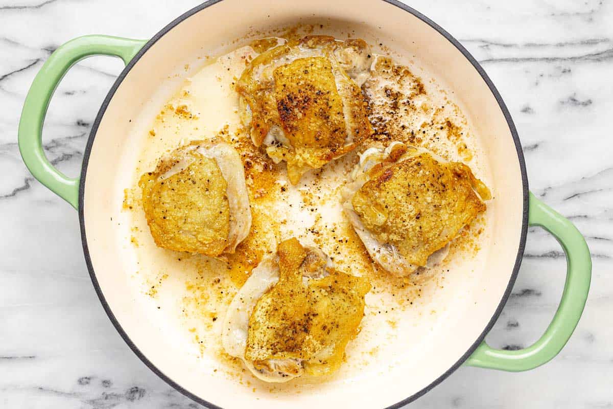 Large pan with 4 sauteed chicken thighs. 