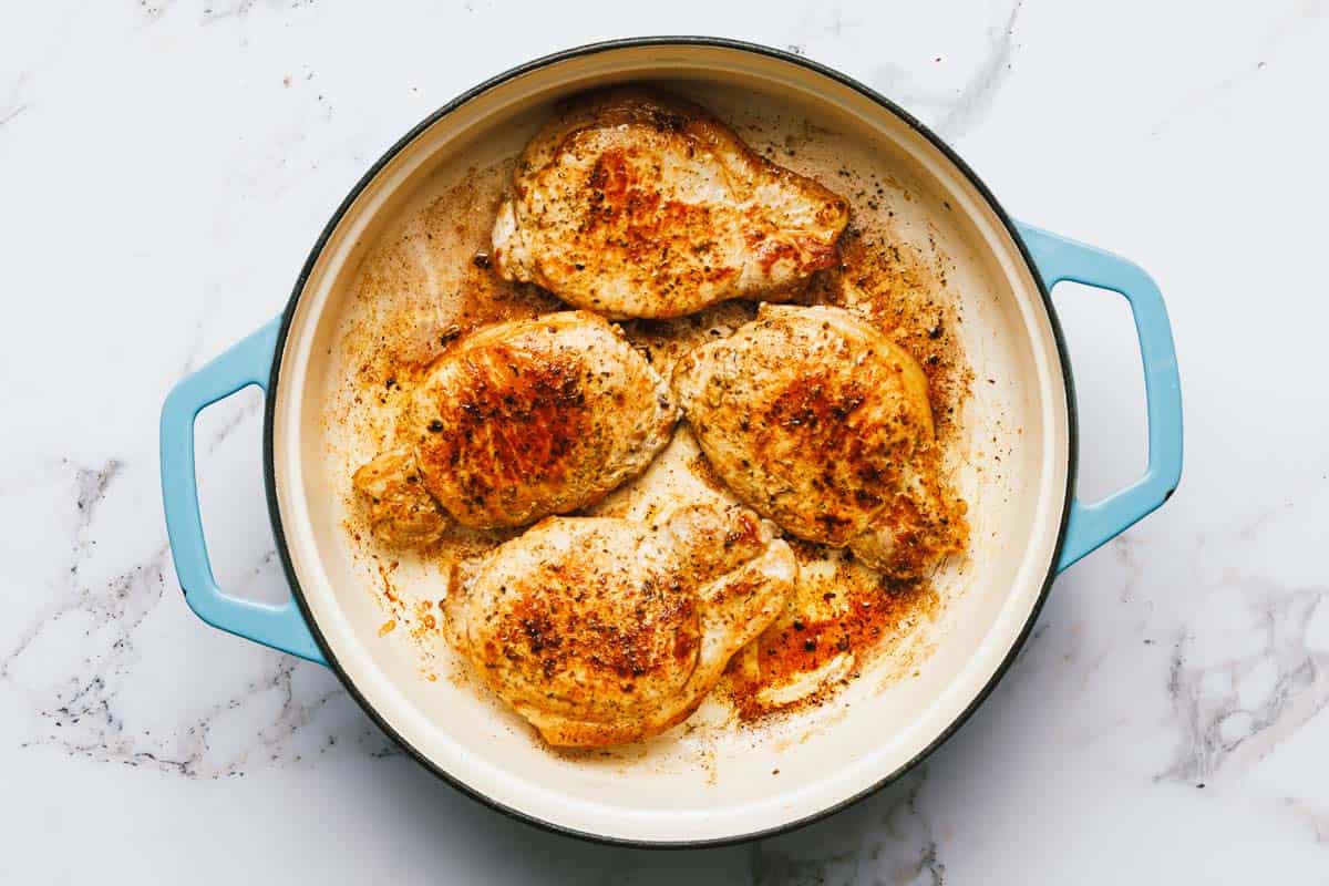 Seared pork chops in a large pan. 