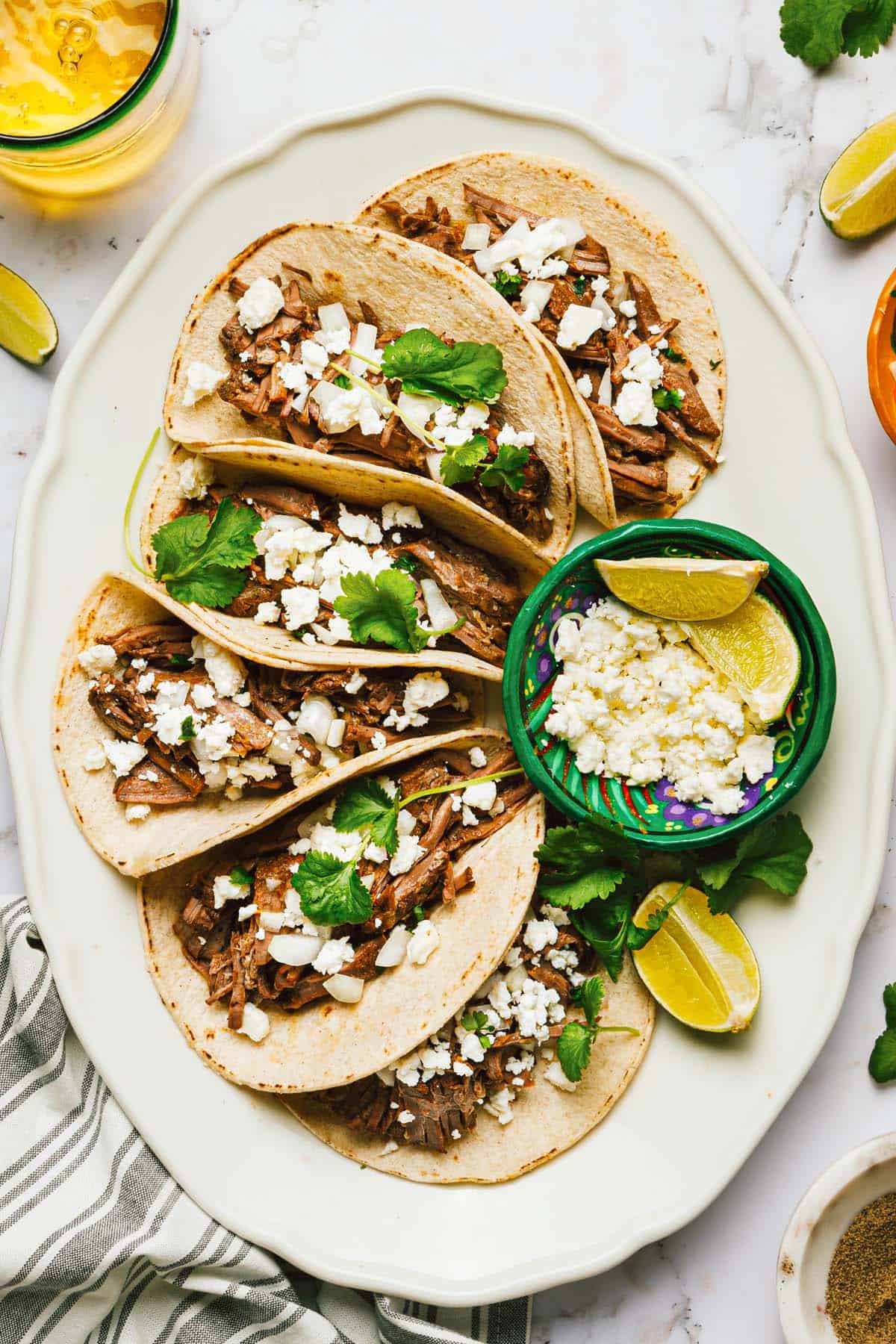 Large platter with shredded beef tacos topped with Cotija cheese. 